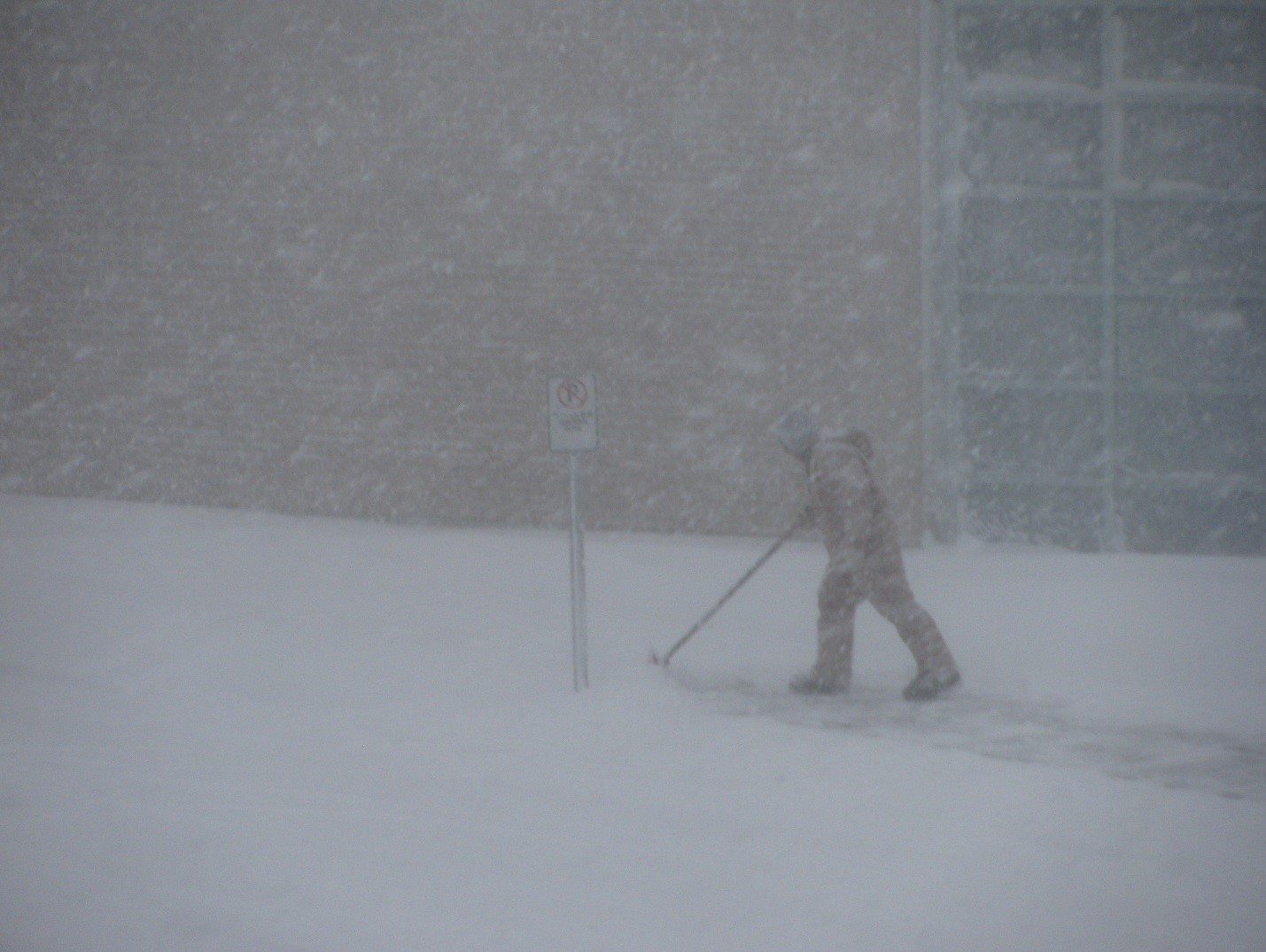 man shovelling in snowstorm