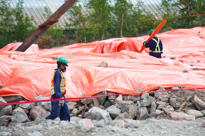 Two workers in personal protective equipment at a demolition site.