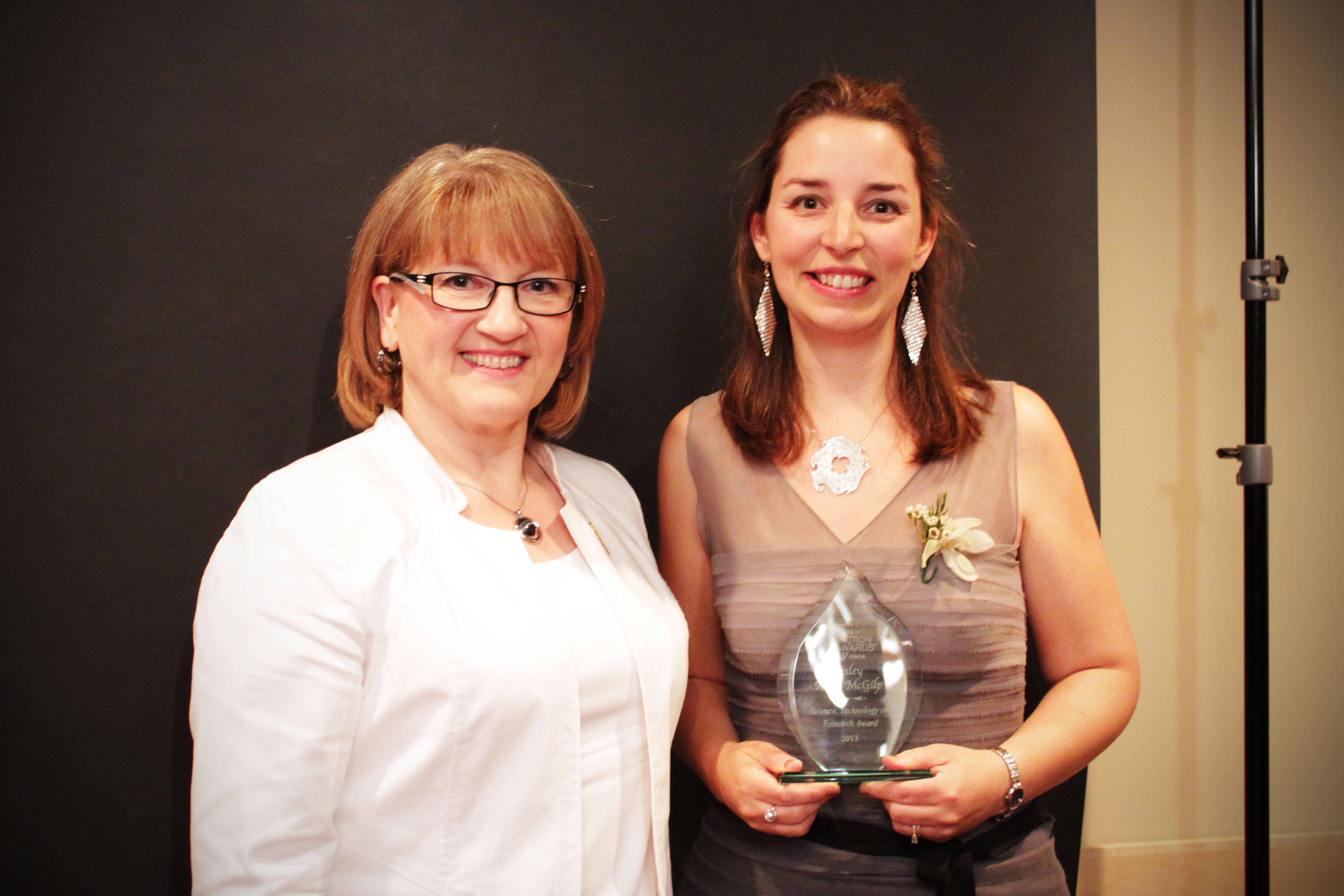 two women, one holding an award