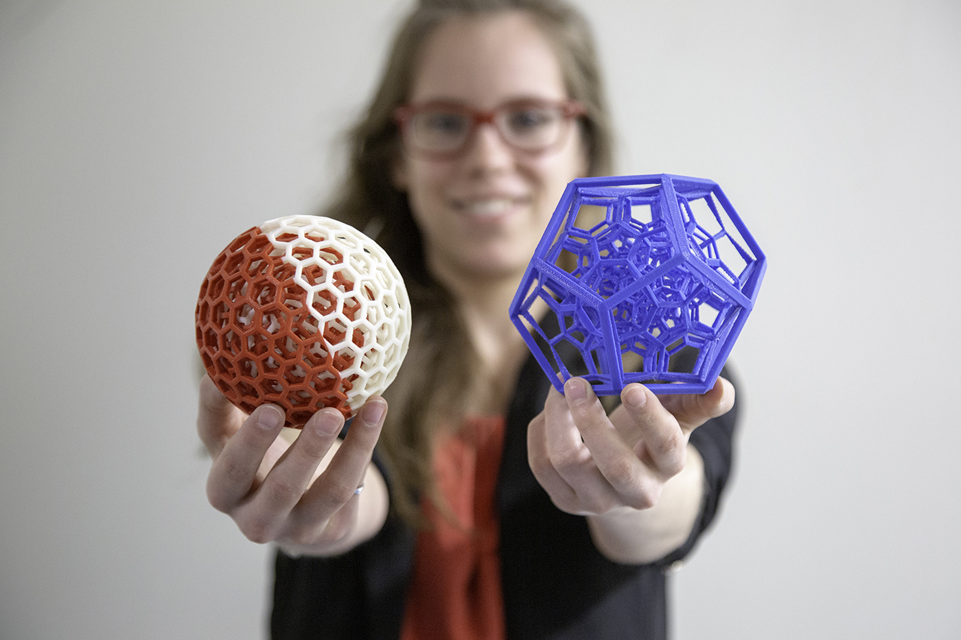 src female engineer holds out additive manufacturing parts