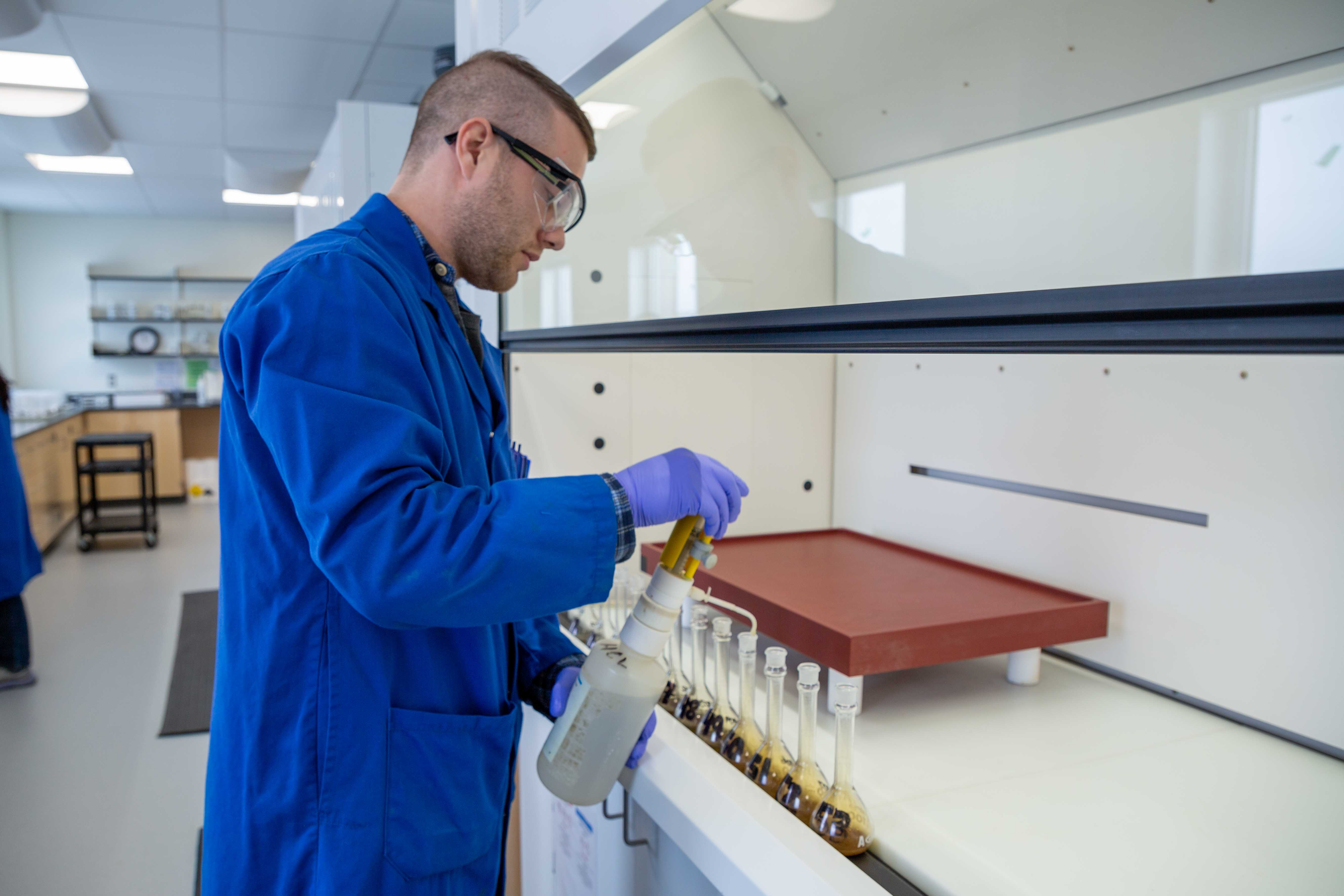 lab technician prepares uranium sample at src geoanalytical lab under fumehood
