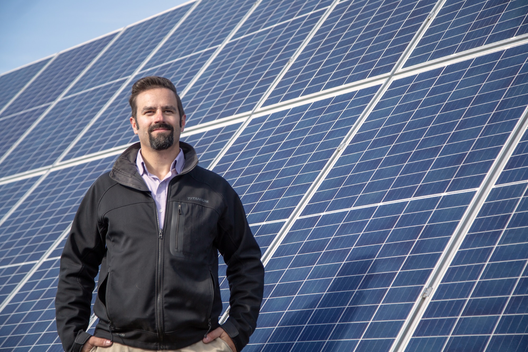 src engineer in training anton farber stands in front of solar array