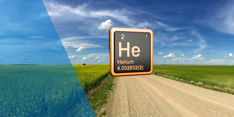 Helium element suspended above a gravel road surrounded by green prairie fields, blue sky and sunshine.