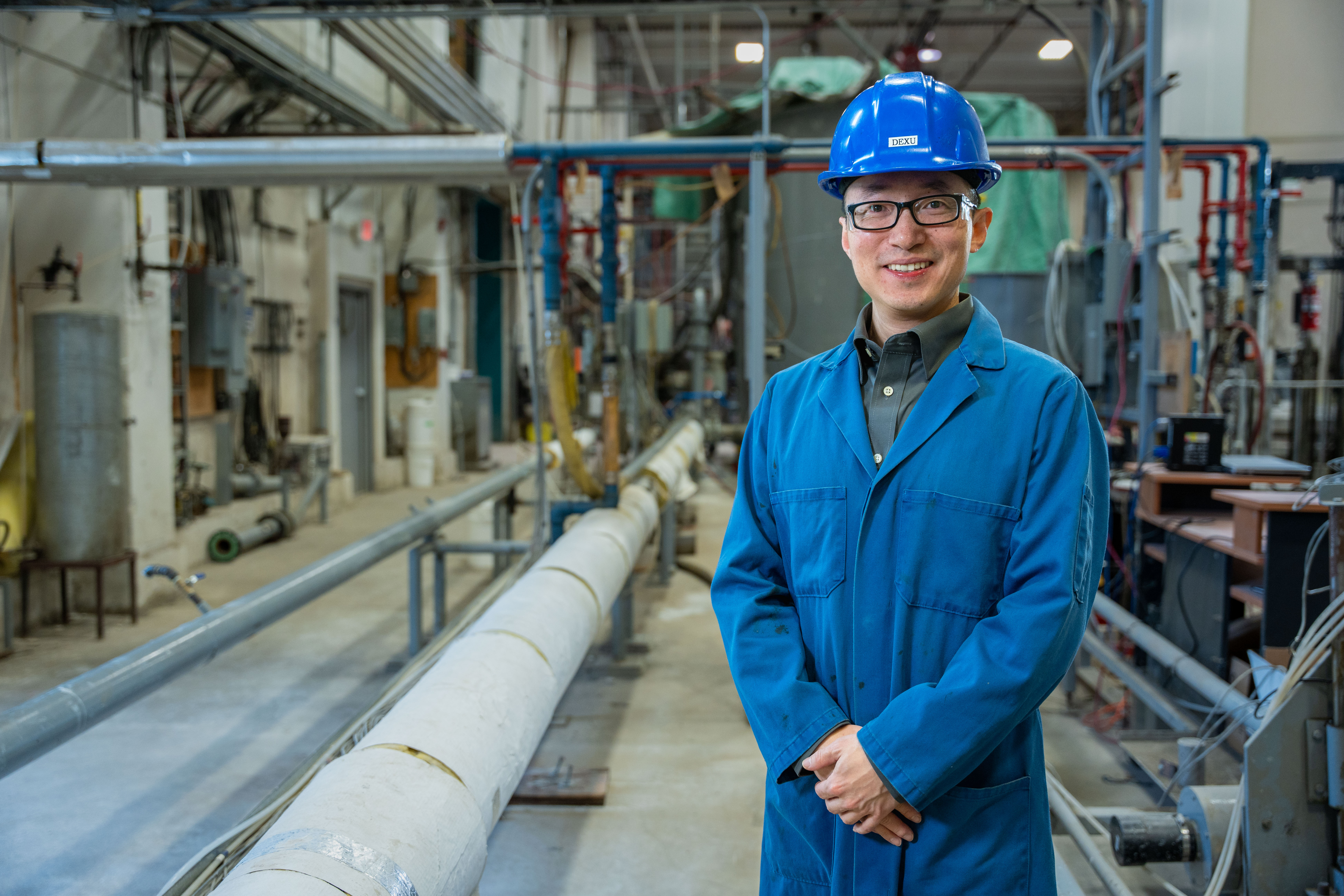 Dexu K stands in front of industrial background at SRC Pipe Flow Facility