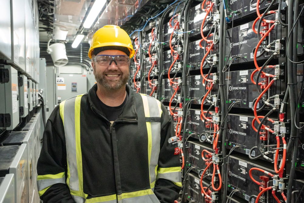 src engineer stands inside of a hybrid energy container alongside battery storage