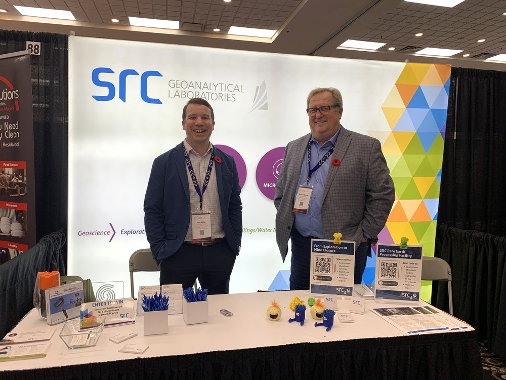 two src employees standing in front of a booth display at a tradeshow