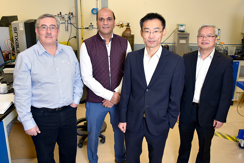 four men stand in a lab