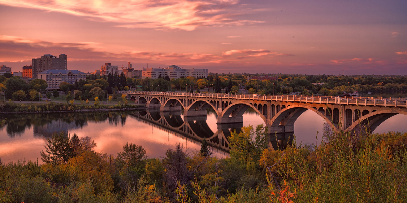 skyline of saskatoon's university bridge at sunset with the leaves on trees beginning to change colour