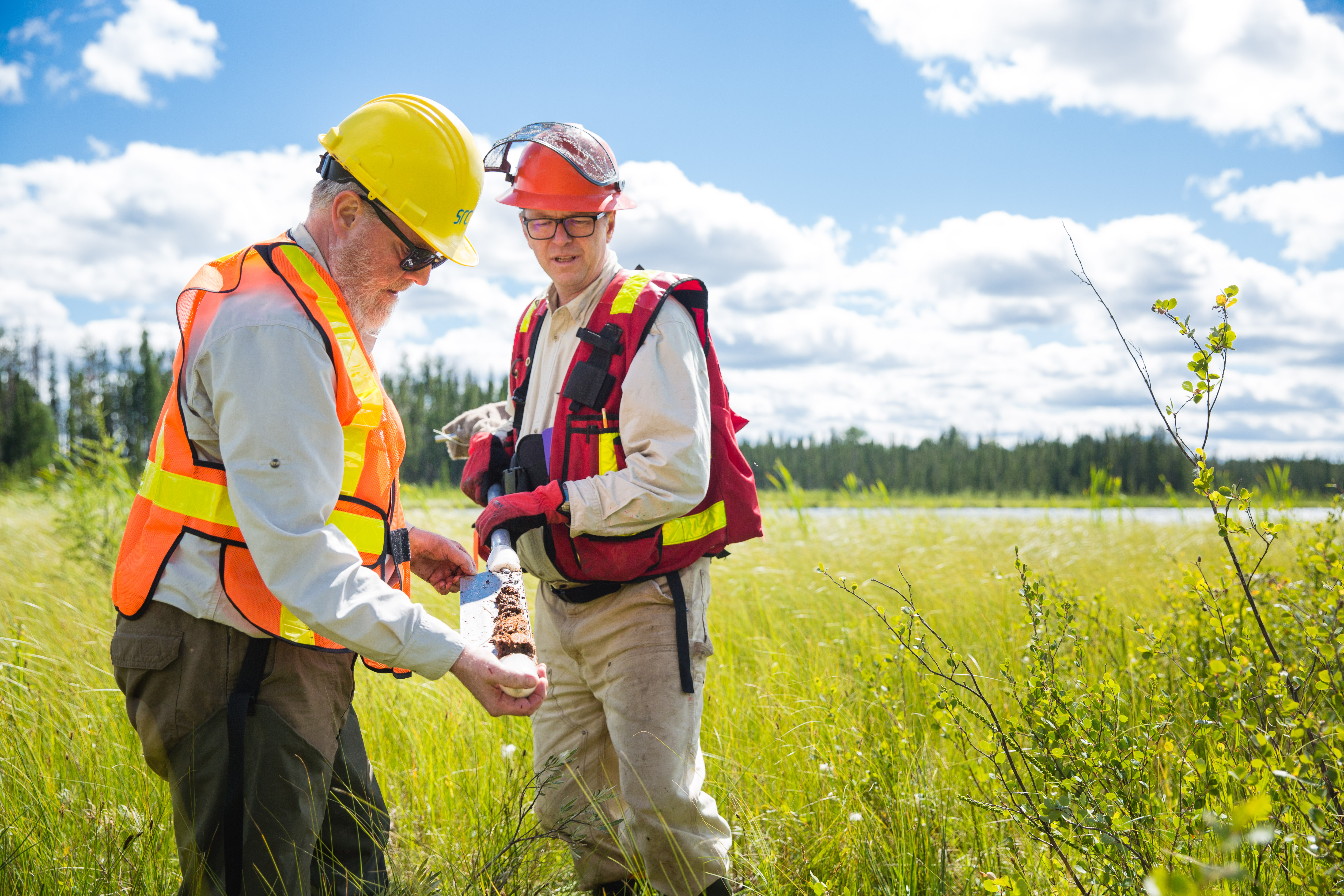 two men look at peat sample