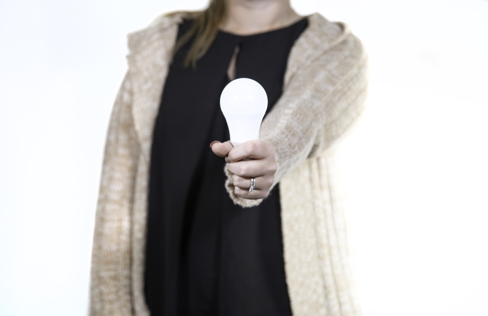 src female employee holding energy-efficient LED light bulb