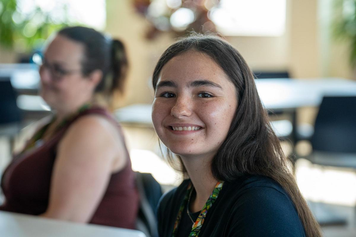 A girl smiling with another woman blurred in the background