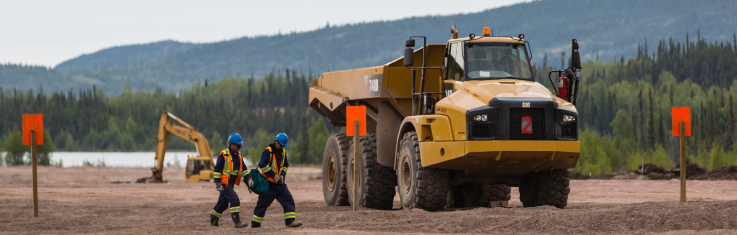 two men in src safety gear walking across lorado mill site next to a big truck