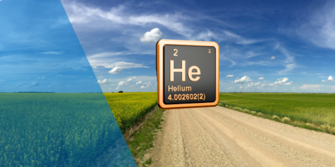 Helium element suspended above a gravel road surrounded by green prairie fields, sunshine and blue sky.