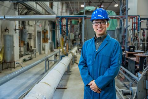 Dexu K stands in front of industrial setting at SRC's Pipe Flow Facility