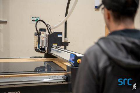 man supervises laser cutter at src