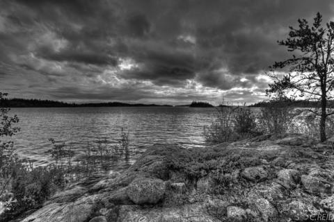View of lake from rugged shore with dramatic clouds