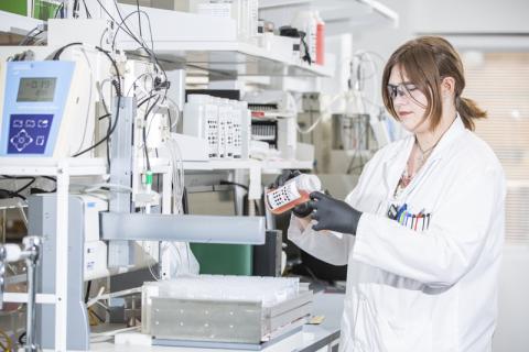 female src employee pours liquid into container for water quality testing