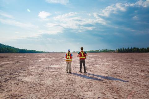 two field workers walk over reclaimed mill site