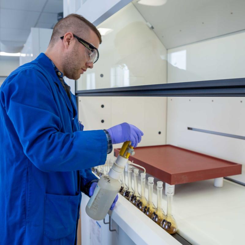 src technologist working with uranium sample under fumehood