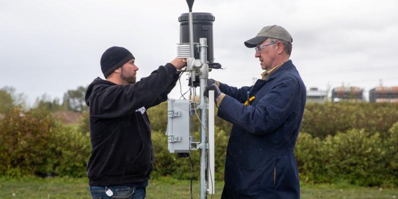 two engineers install solar panel at src weather station
