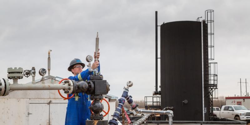 src technician inspects well head at oil site