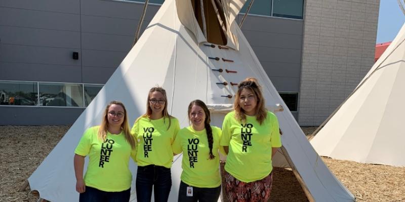 four female src students stand in front of a tipi
