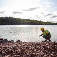 field worker taking water sample from lake