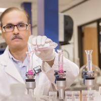 lab technician pours pink liquid into test tubes