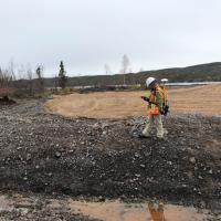 gamma survey technician walking across rocky remediated area with survey instrumentation