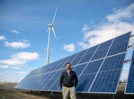 src research engineer stands in front of wind turbine and solar panels