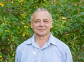 Man smiling with bushes behind him